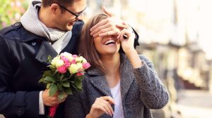 Homme avec un bouquet cachant les yeux d'une femme