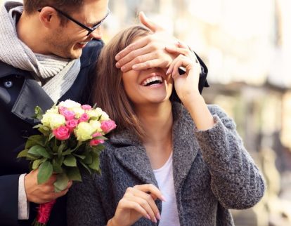 Homme avec un bouquet cachant les yeux d'une femme